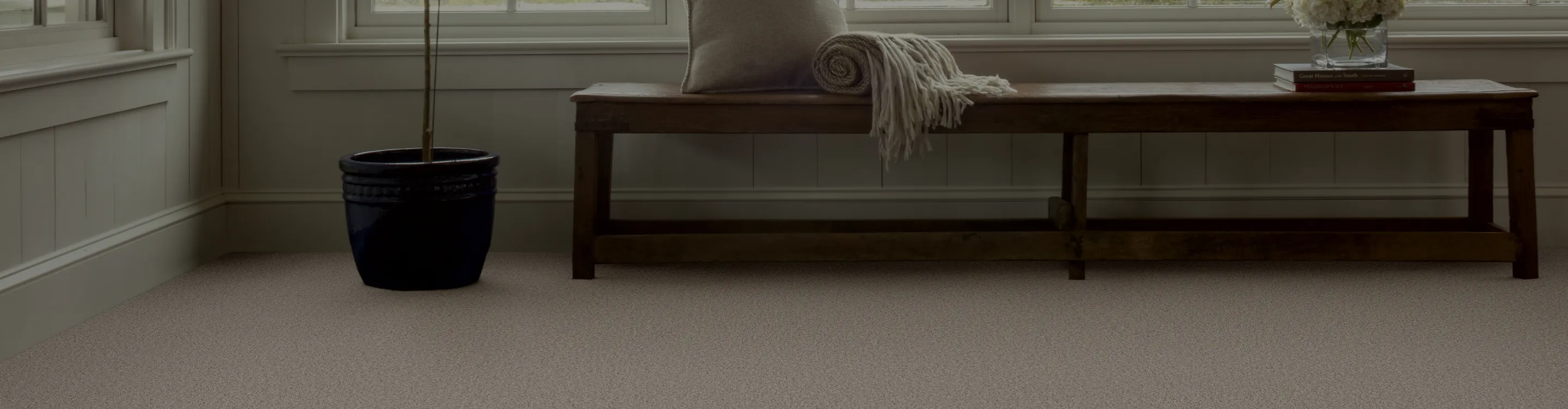 Foyer with brown carpet and bench